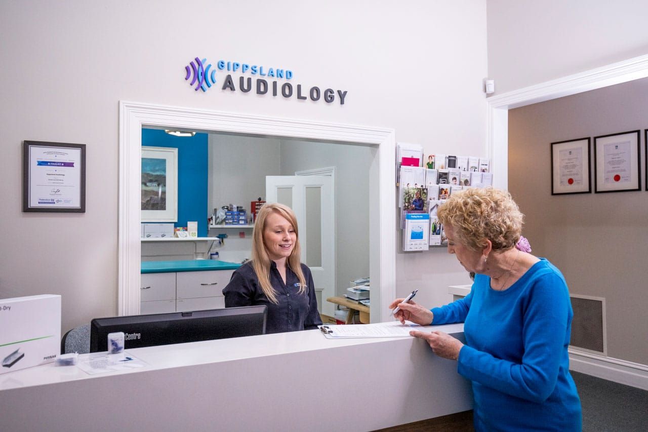 A Woman Signing Documents Before Seeing Her Audiologist