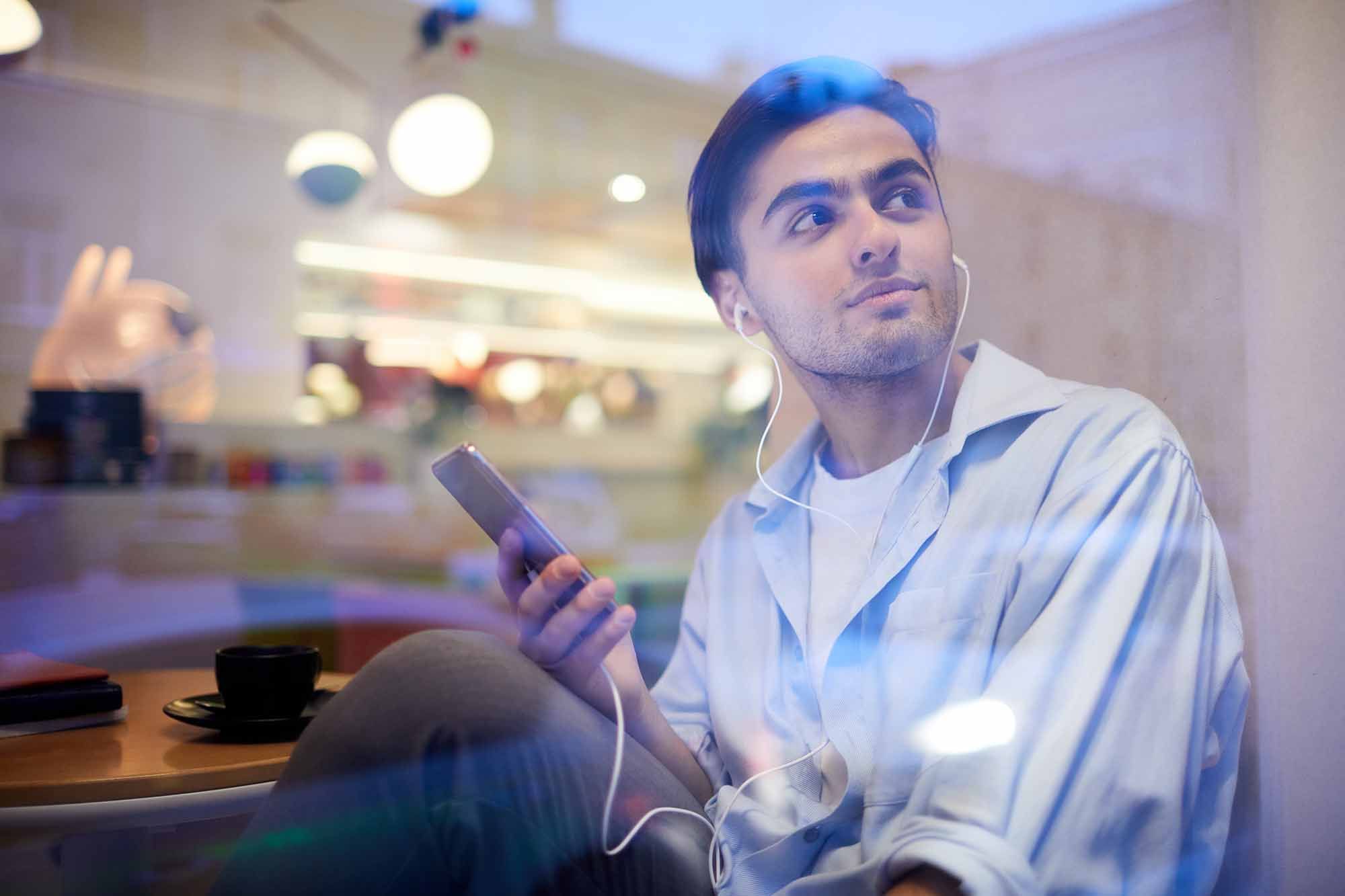 A Young Man Listens to Music While at a Cafe