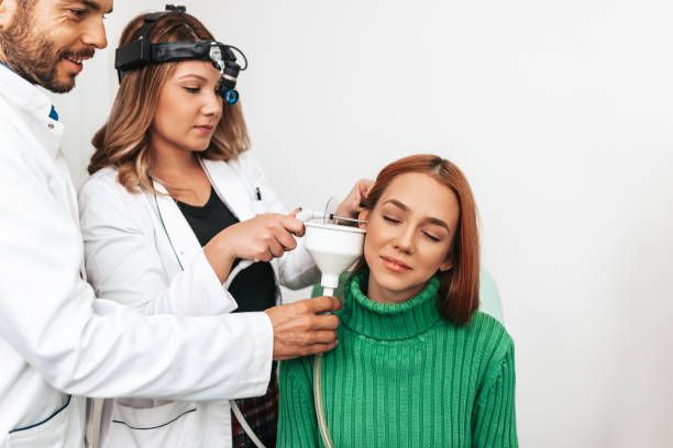Young adult redhead woman at medical examination or checkup in otolaryngologist's office. Ear irrigation and earwax removal.