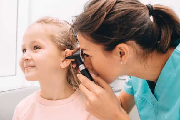 Audiologist examining a little patient with an otoscope, hearing exam of the child