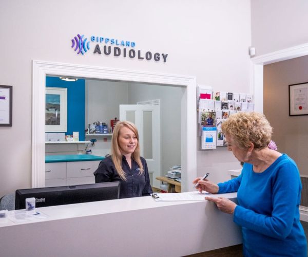 A Woman Signing Documents Before Seeing Her Audiologist